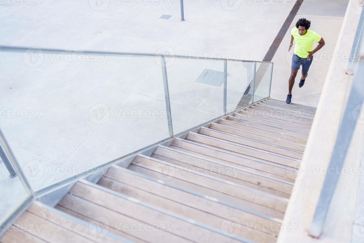 Black man running upstairs outdoors. Young male exercising. photo