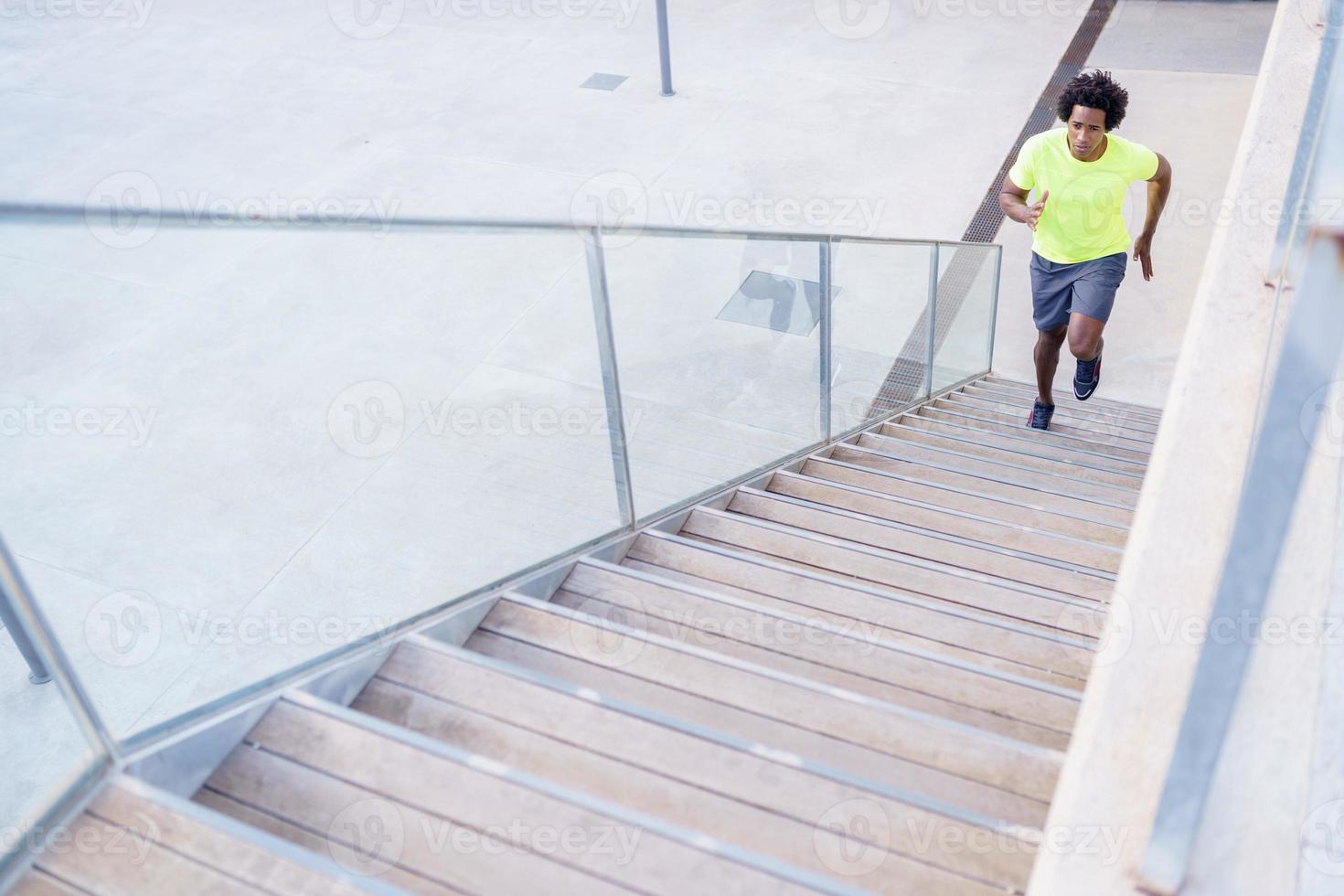 Black man running upstairs outdoors. Young male exercising. photo