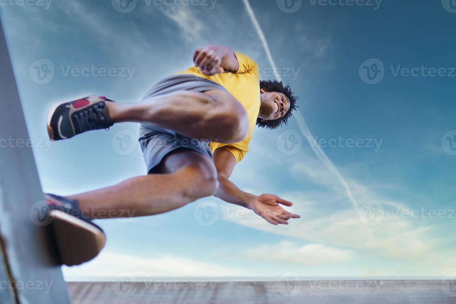 View from below of black man jumping on his run. photo