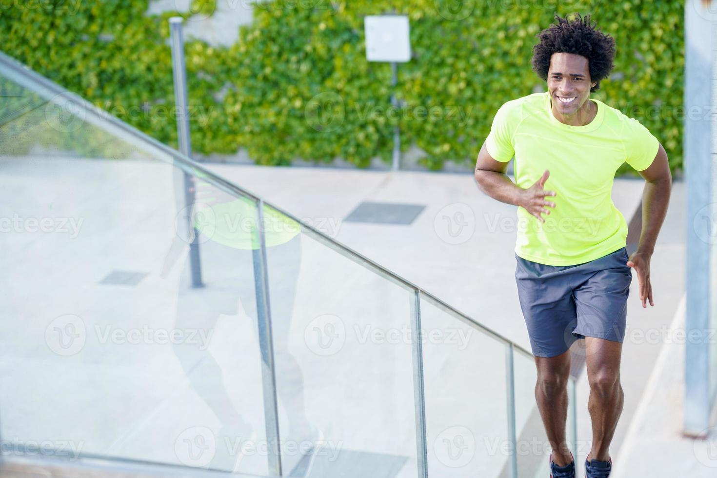 Black man running upstairs outdoors. Young male exercising. photo