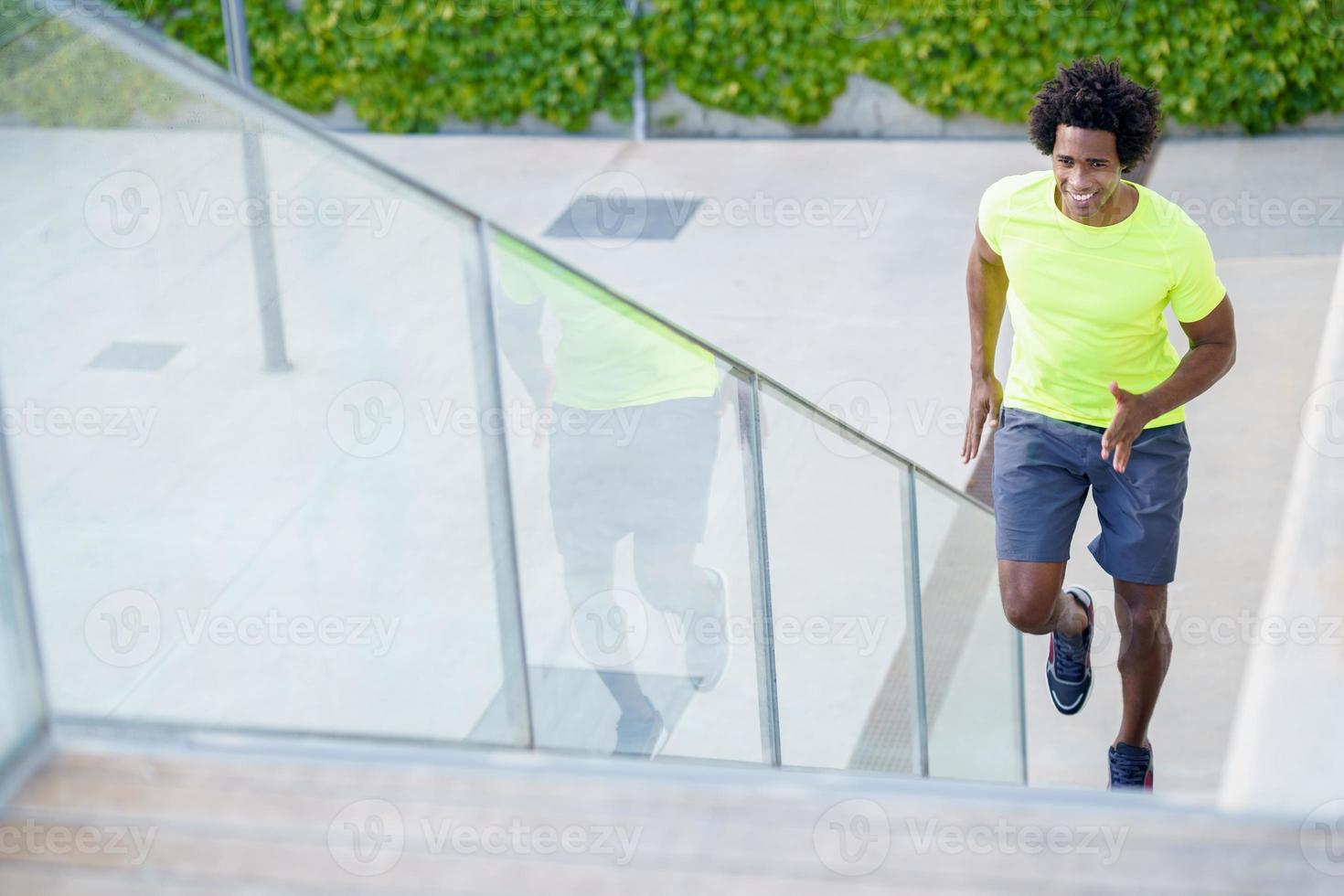 Black man running upstairs outdoors. Young male exercising. photo