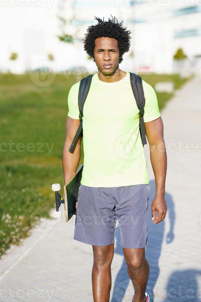 hombre negro va a hacer ejercicio en ropa deportiva y una patineta