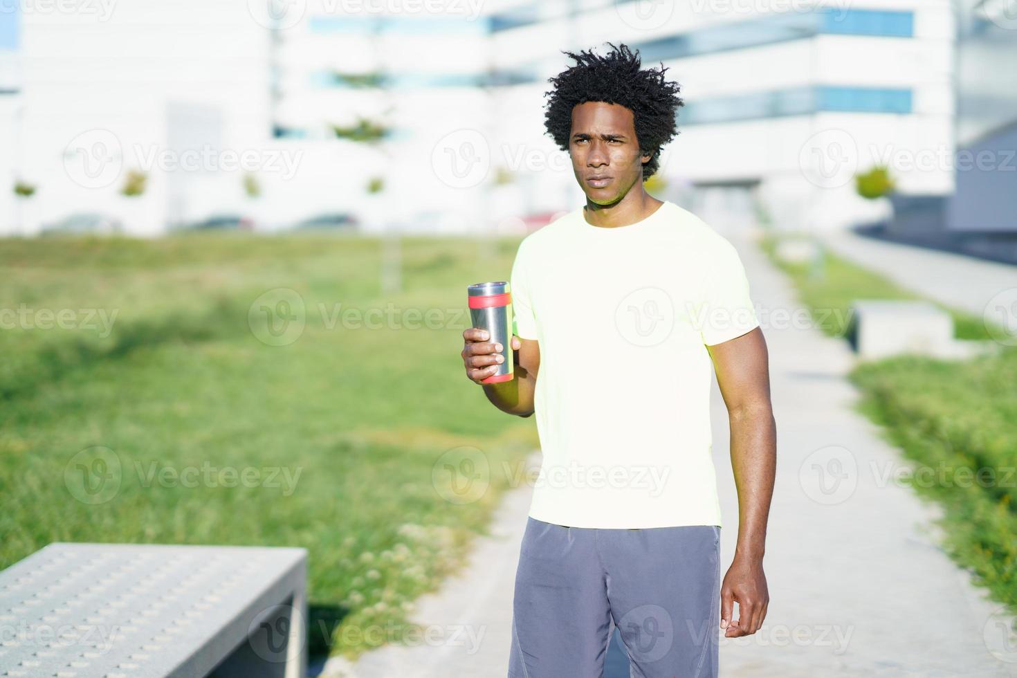 hombre negro bebiendo durante el ejercicio. corredor tomando un descanso de hidratación. foto