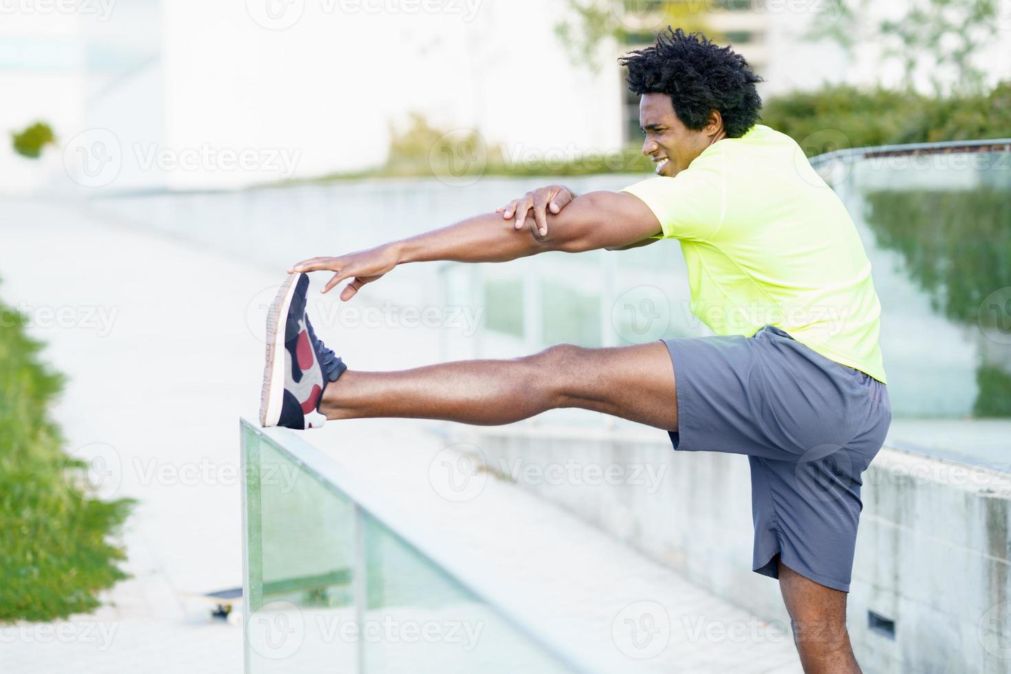 Black man with afro hair doing stretching after running outdoors. photo