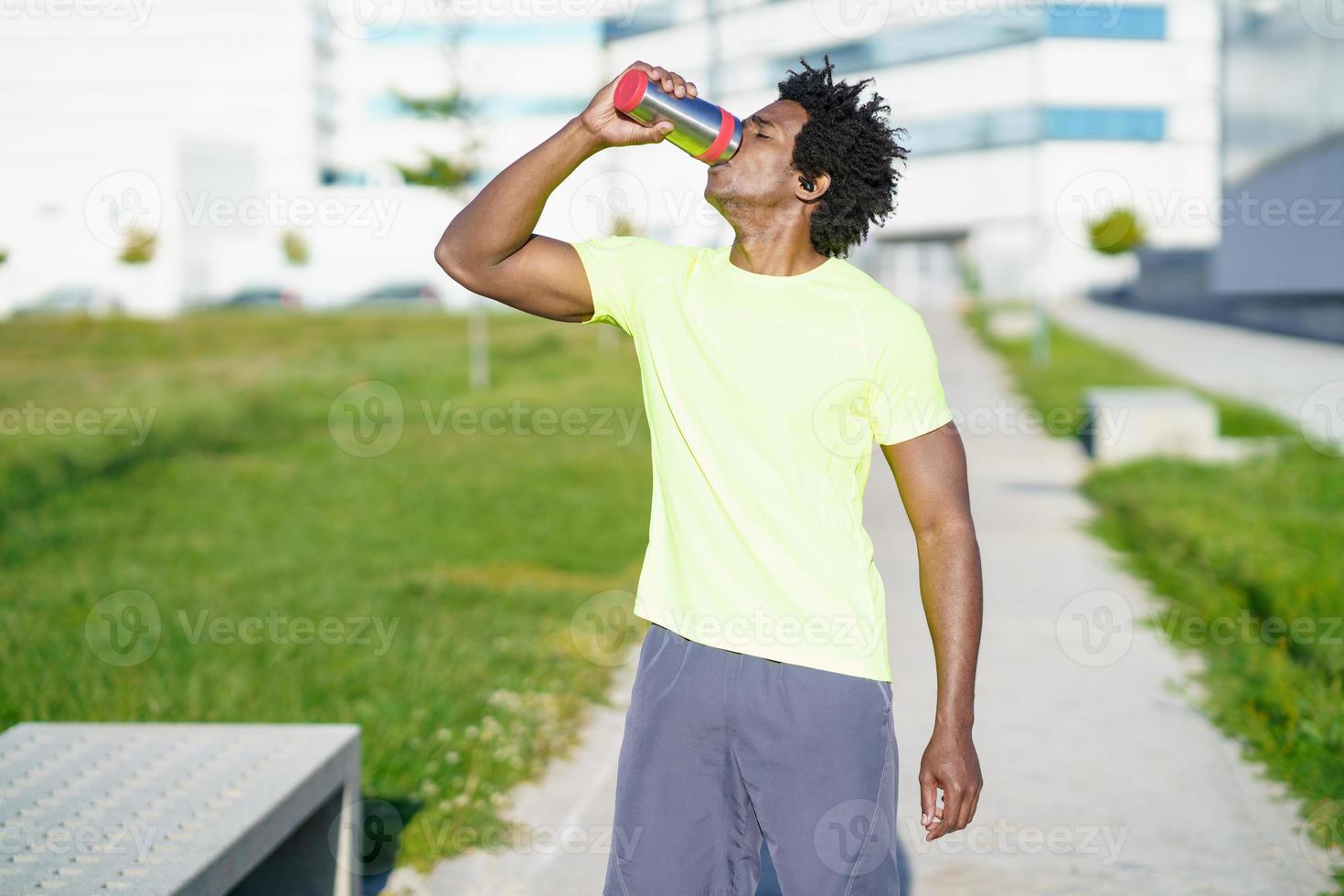 hombre negro bebiendo durante el ejercicio. corredor tomando un descanso de hidratación. foto