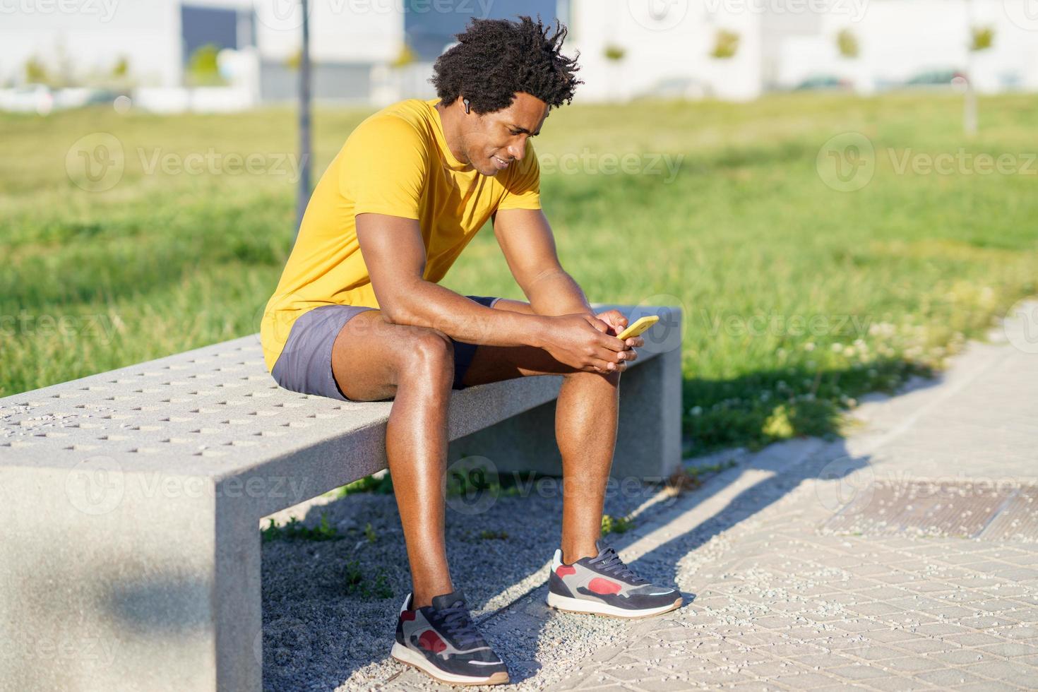 Hombre negro consultando su teléfono inteligente con alguna aplicación de ejercicio foto