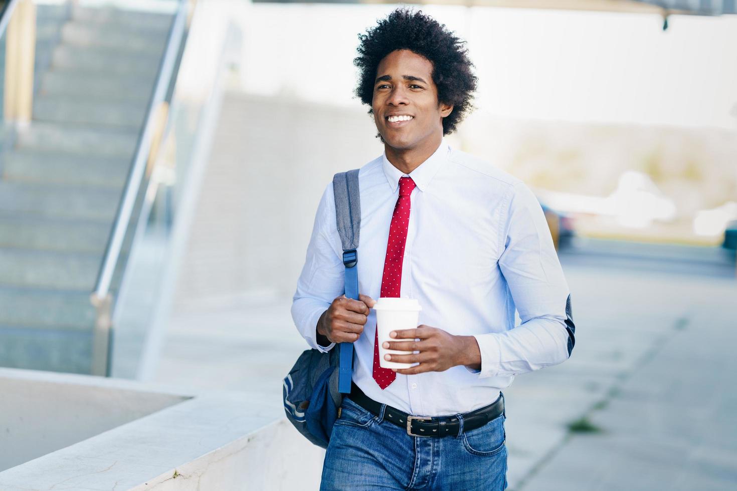 sonriente empresario negro con un vaso para llevar. foto