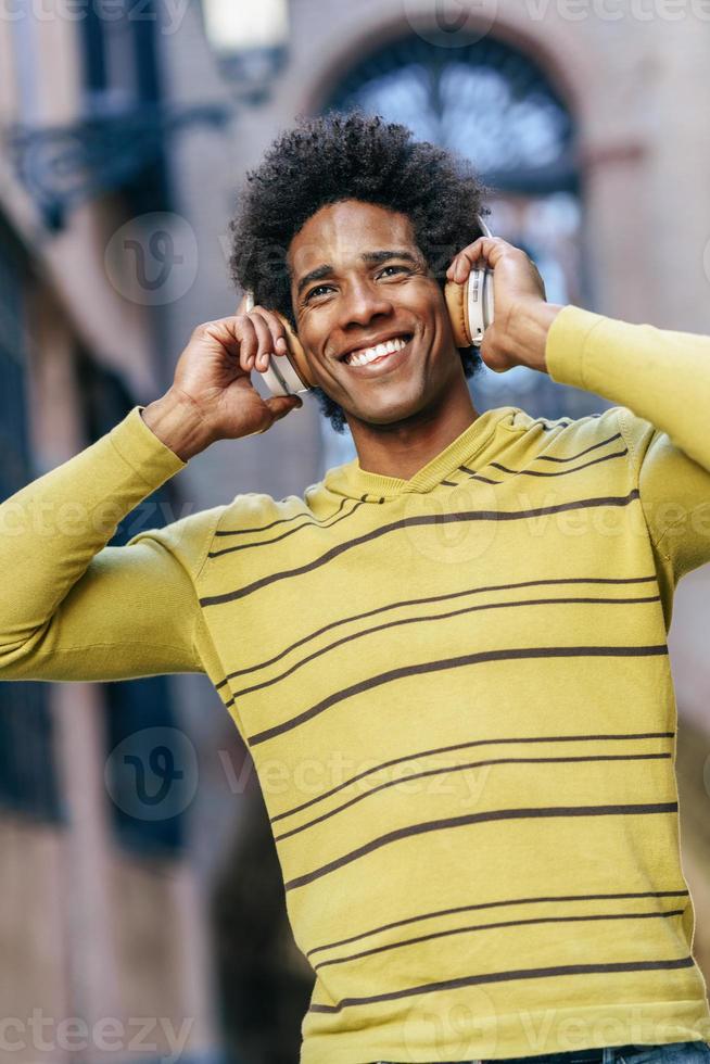 Black man listening to music with wireless headphones photo