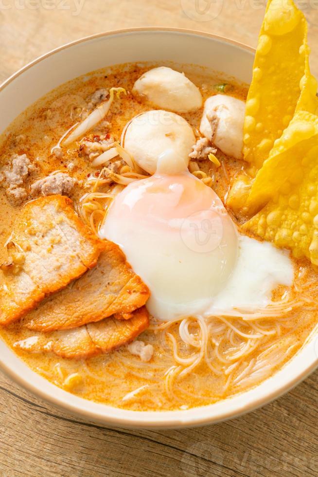 Rice vermicelli noodles with meatball, roasted pork and egg in spicy soup photo