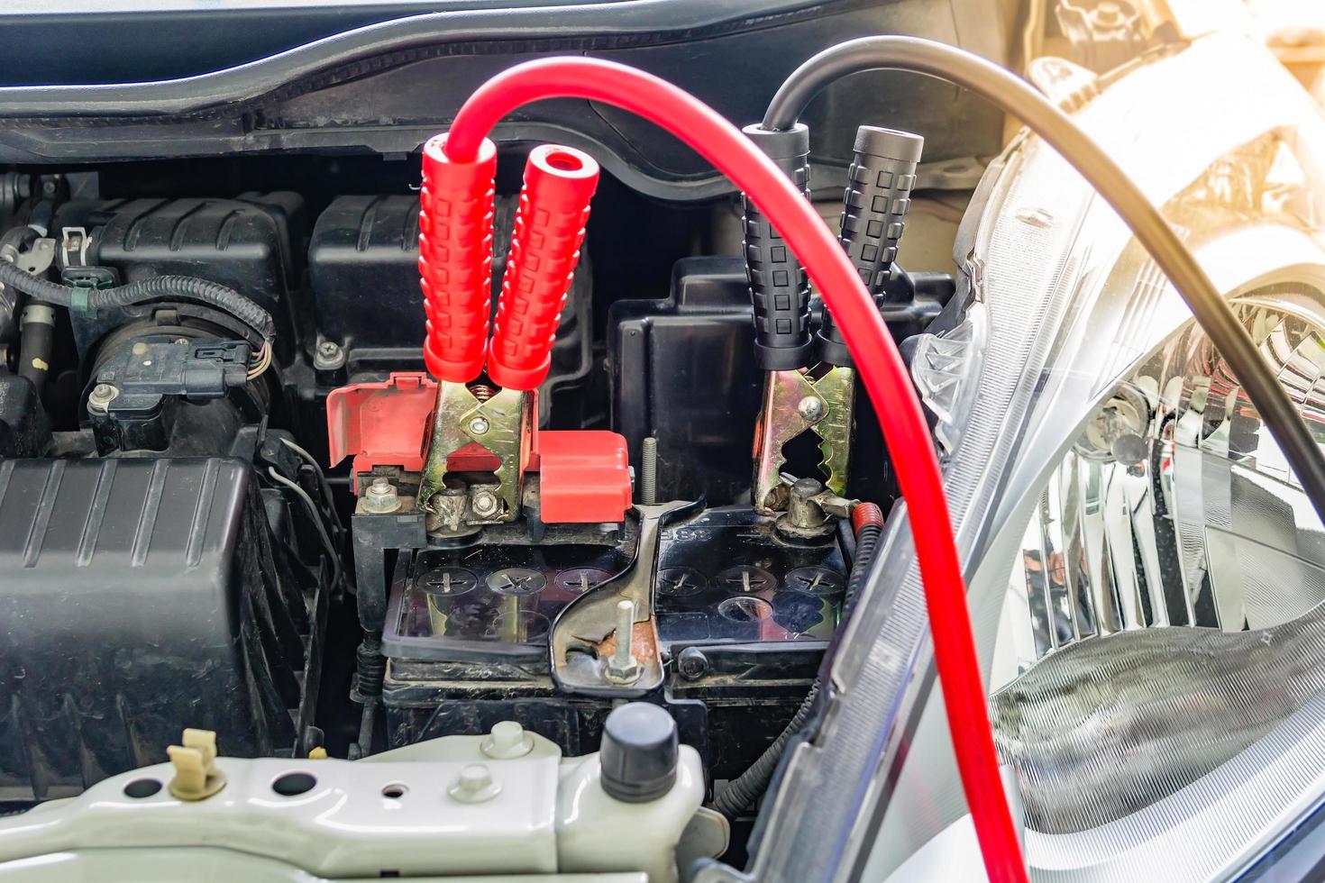 Carga de la batería del coche con cables de puente a través de la electricidad. foto