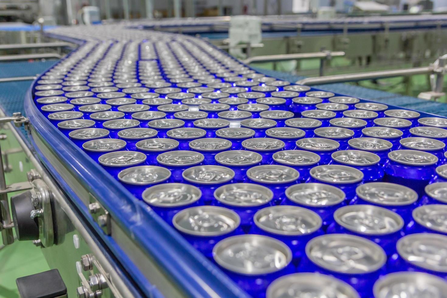 Latas envasadas en la cinta transportadora en la fábrica de bebidas. foto