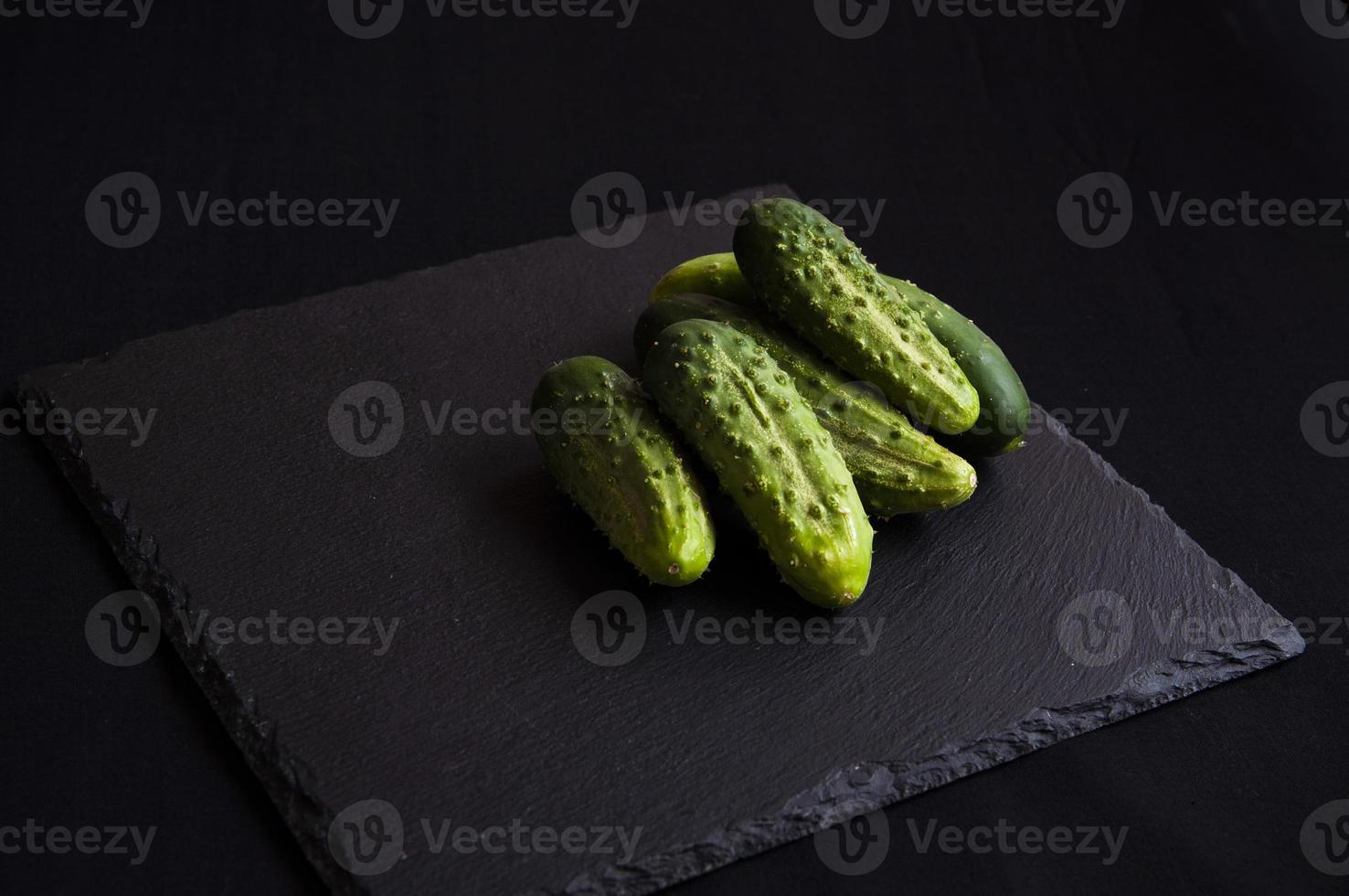 Natural fresh green cucumbers from a home garden on a black background photo