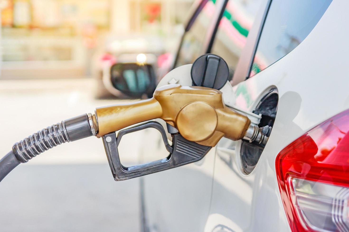 Coche blanco en la gasolinera se está llenando de combustible en Tailandia foto