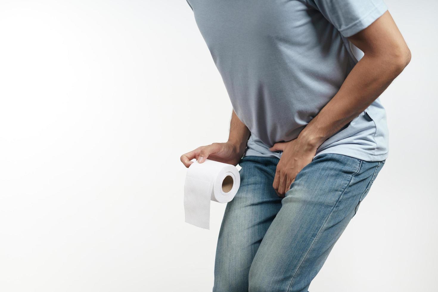 Young man holding his crotch and tissue paper suffering from Diarrhea. photo