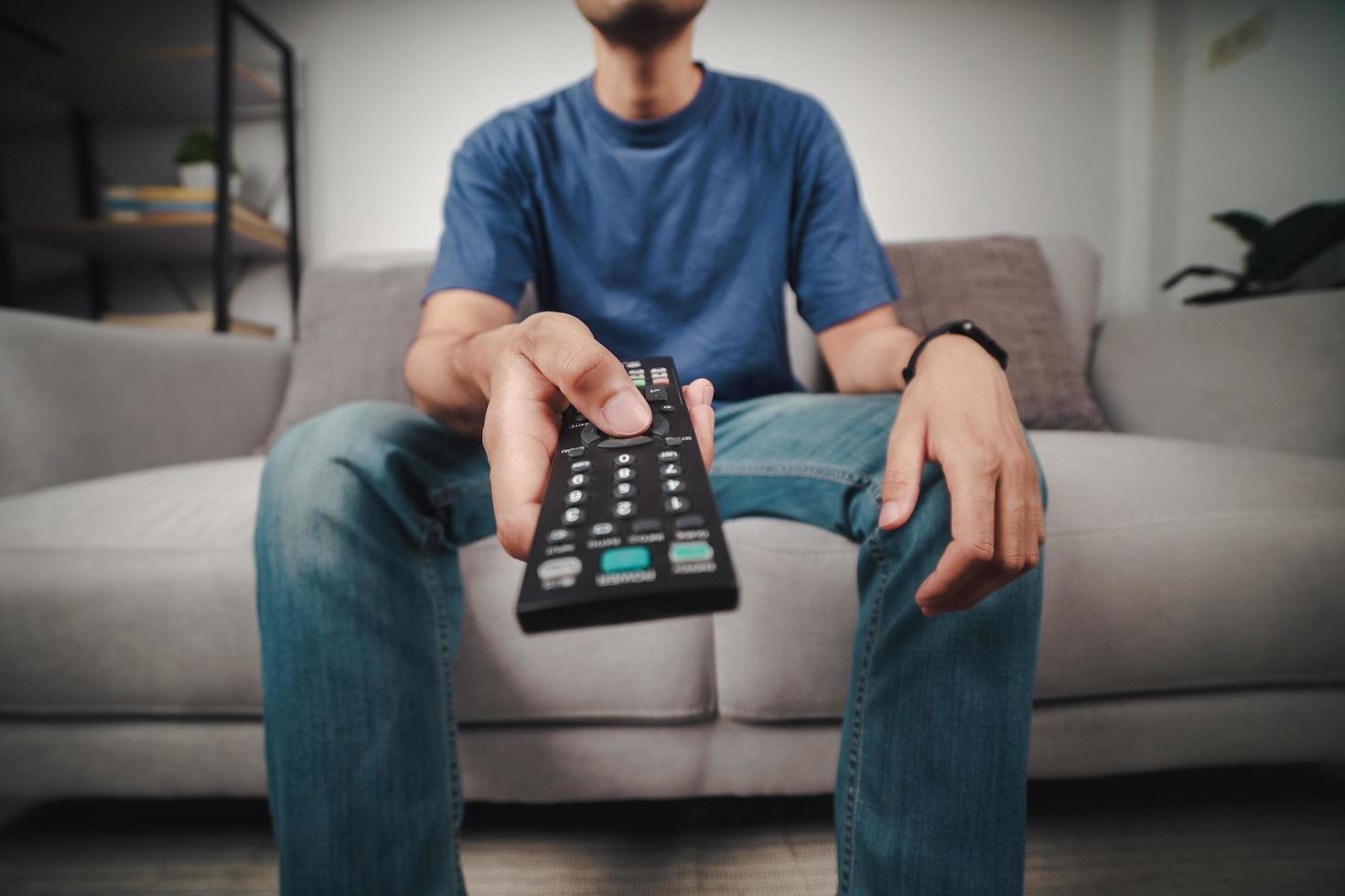 Man hold and press the TV remote controller button. photo