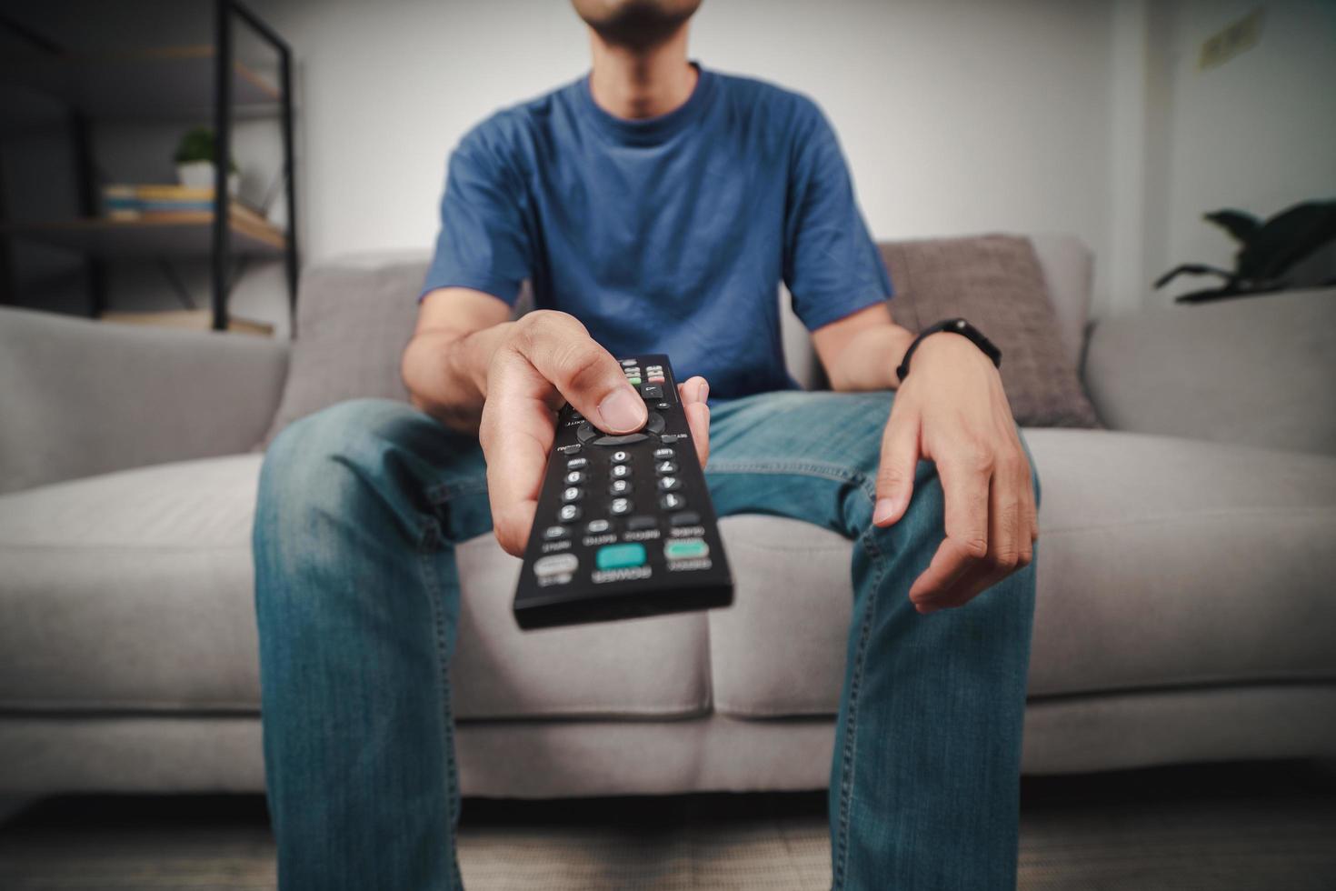 hombre mantenga presionado y presione el botón del control remoto del televisor. foto