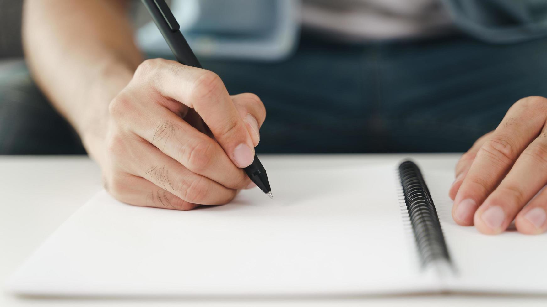 Close up of man hands writing down on the notepad, notebook using pen. photo