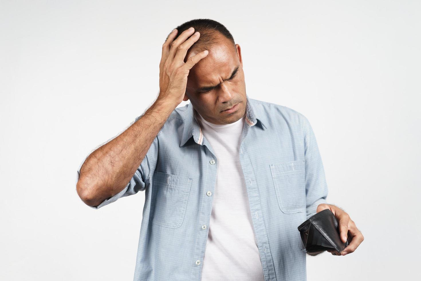 Upset man holding and looking inside his empty wallet. no money. photo