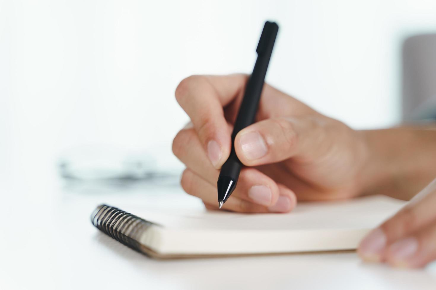 Cerca de las manos del hombre escribiendo en el bloc de notas, cuaderno con lápiz. foto