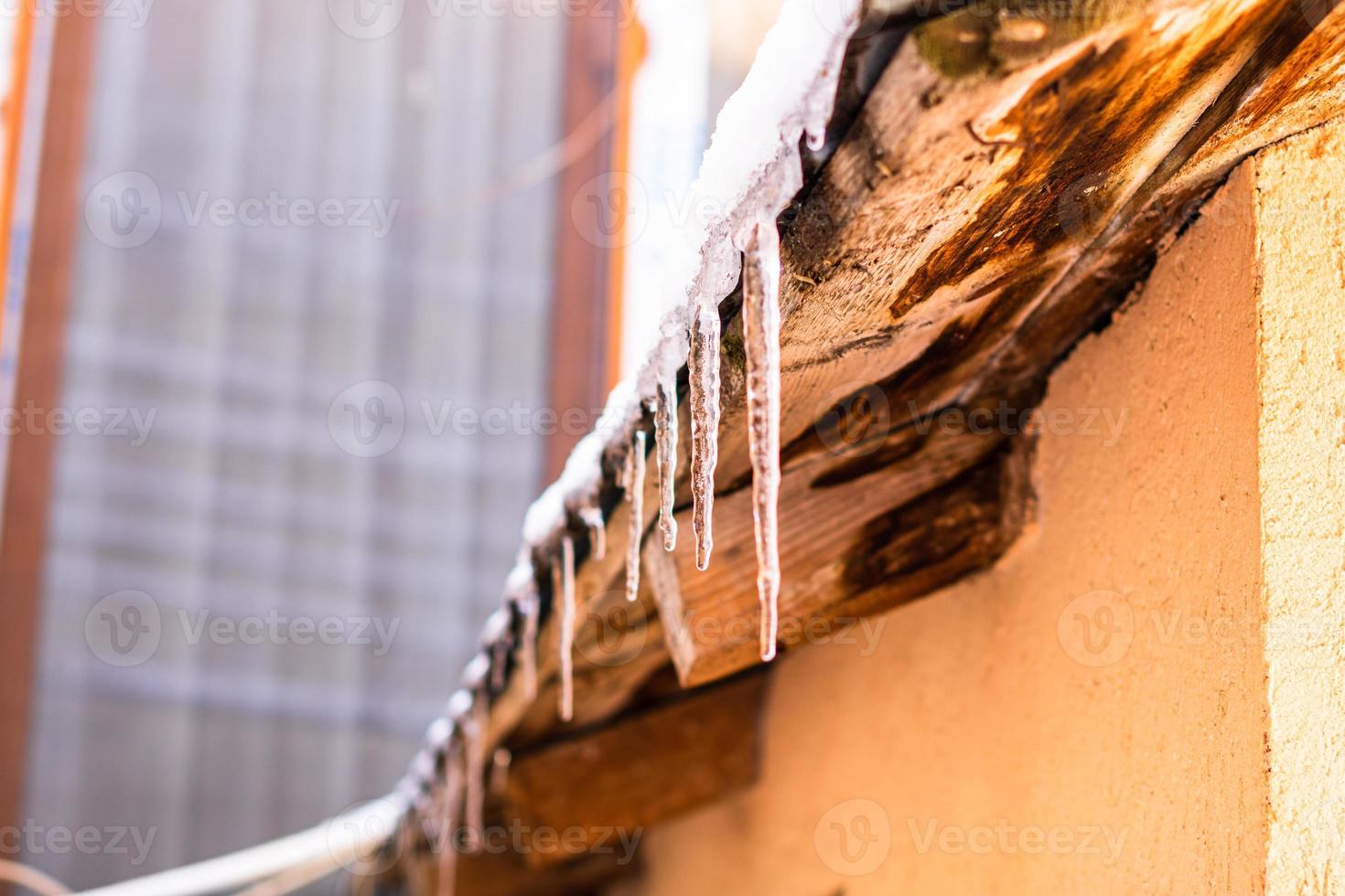 Roof covered with snow, icicles on roof isolated close up. photo