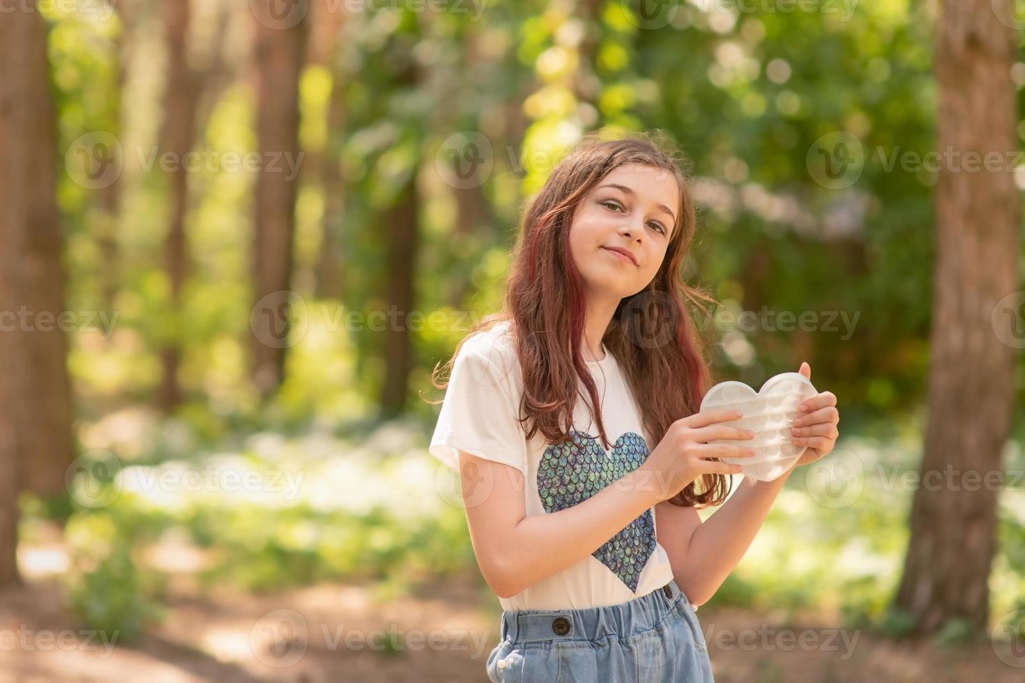 niña sostiene en sus manos un juego pop it en forma de corazón foto