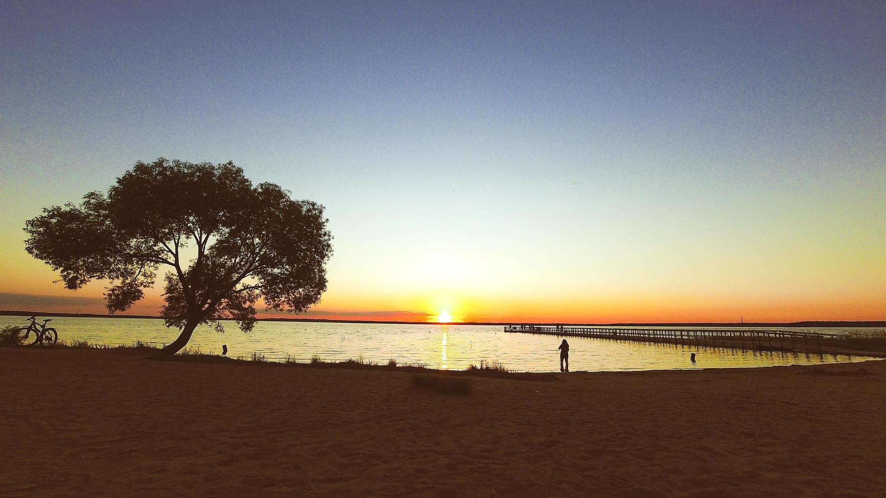 persona en la distancia admira la puesta de sol y toma una fotografía foto