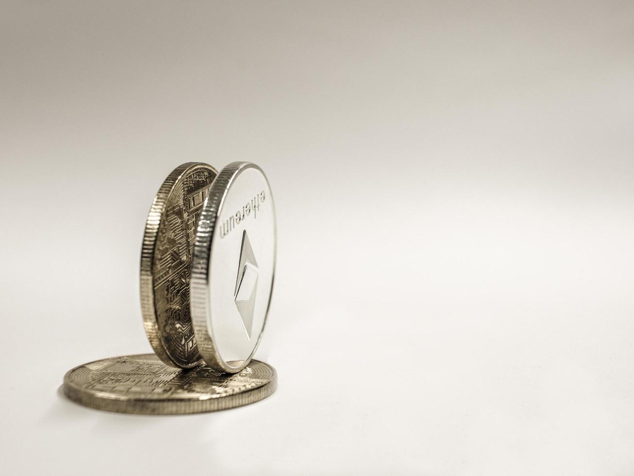 Ethereum coin stand on golden bitcoin on a white background photo