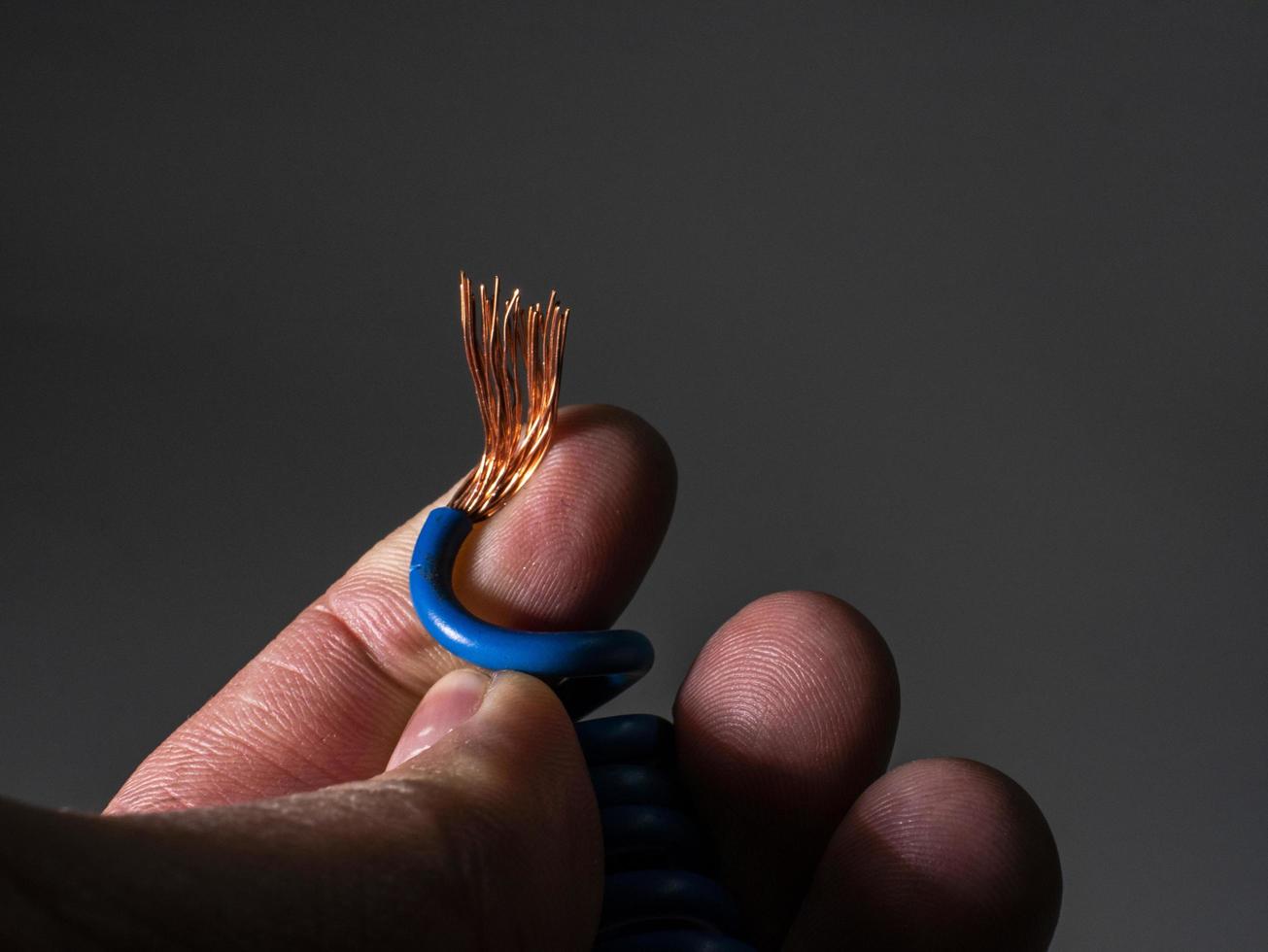 Blue wire bare at the end close up in the hand of a man photo