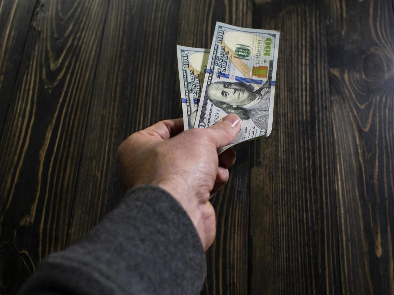 Hand with money on a wooden background photo