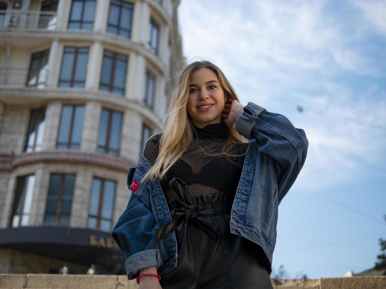 Atractiva chica rubia sonriendo en el fondo de un edificio moderno foto