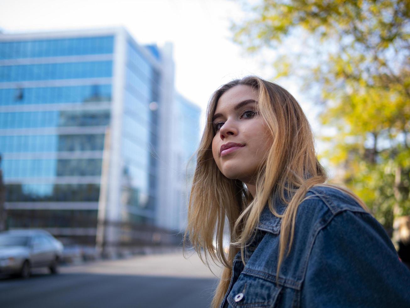 girl with flowing hair in a denim jacket outdoors photo