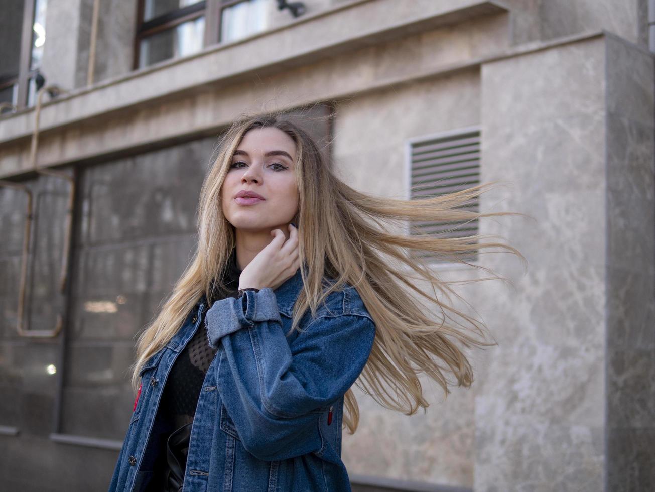 Chica atractiva con un cabello precioso en una chaqueta de mezclilla foto