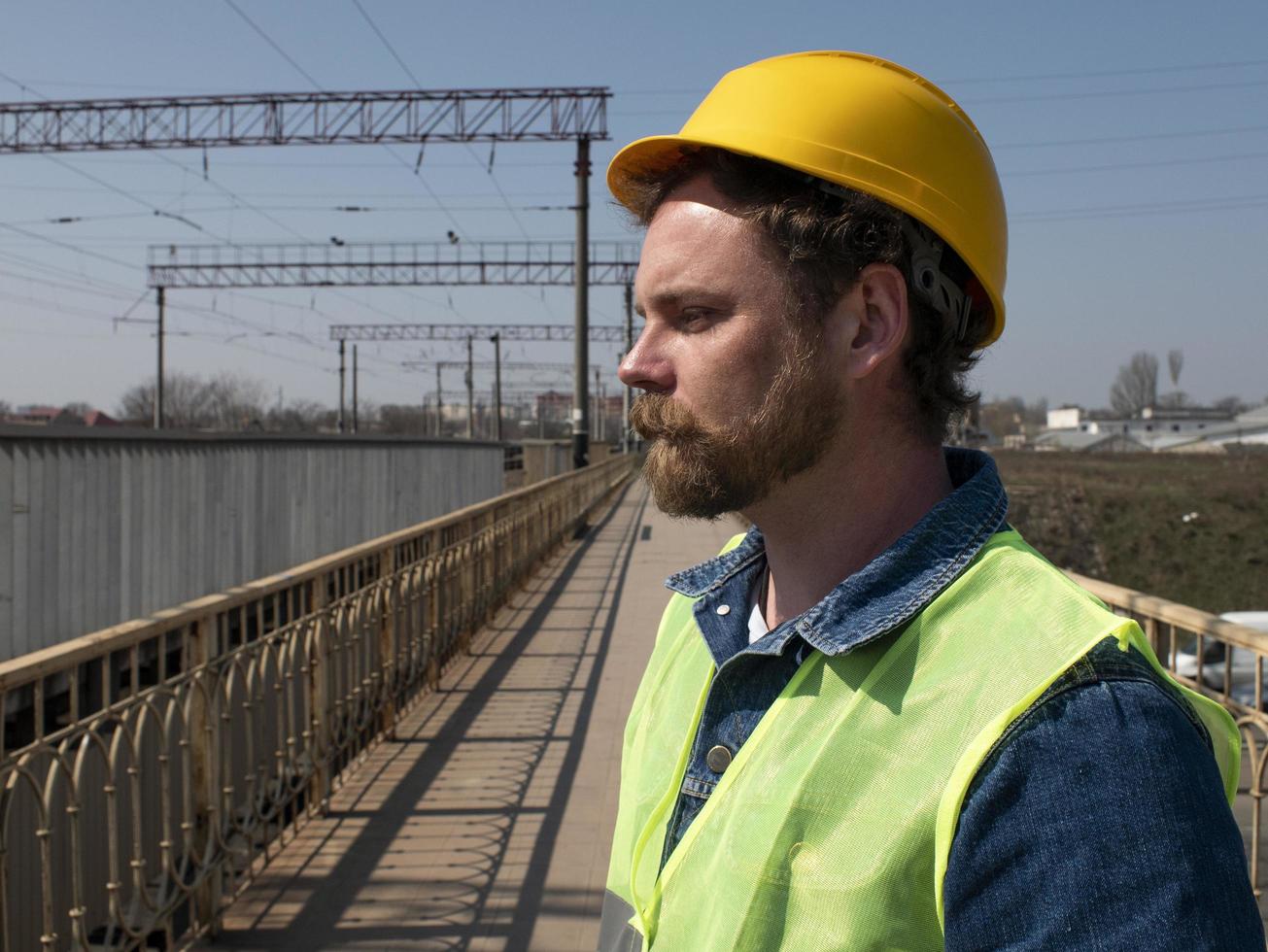 A man with a beard and mustache in a helmet stands on a bridge photo