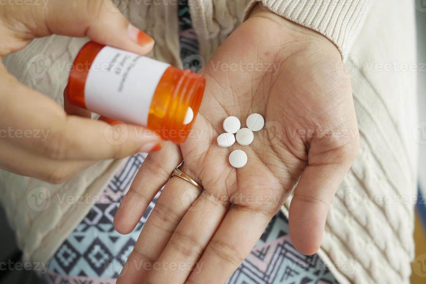 Cerca de la mano de la mujer tomando pastillas foto