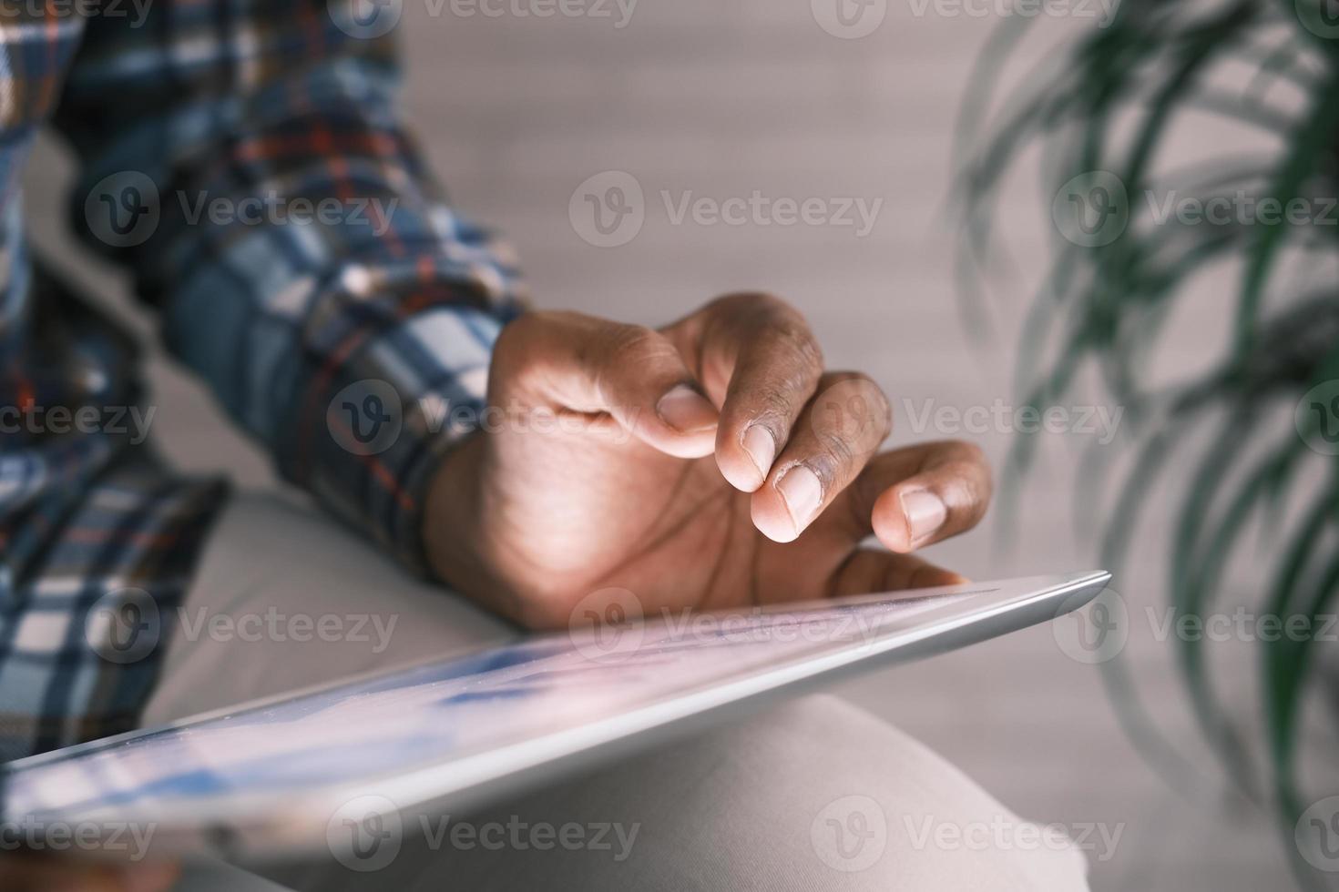 La mano del hombre trabajando en una tableta digital en el escritorio de la oficina, foto