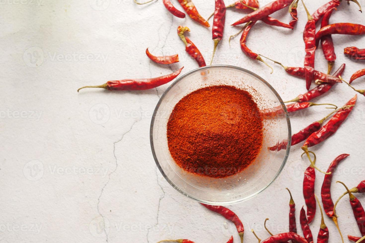 Chili powder and dried peppers on white background. photo