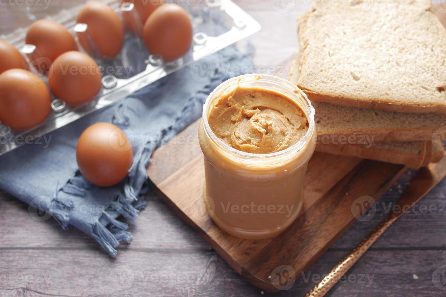 top view of peanut butter and a bread on plate on black background photo