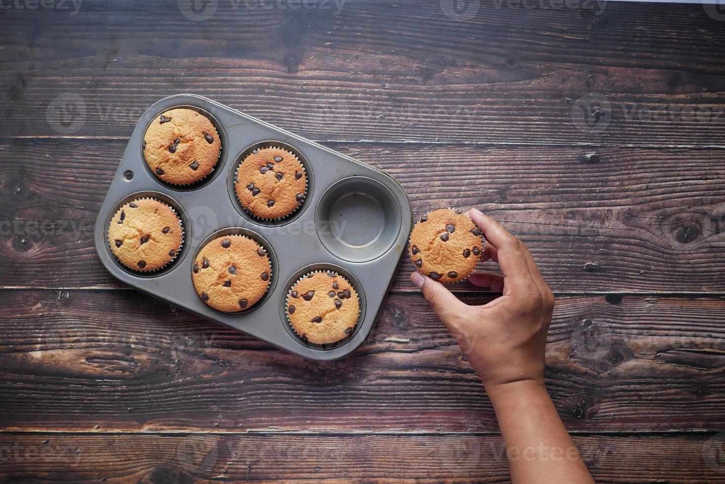 Top view of man hand holding chocolate cup cake on table photo
