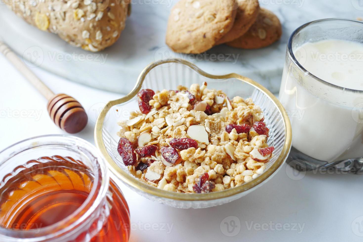 Desayuno de cereales en un tazón, pan y miel sobre fondo blanco. foto