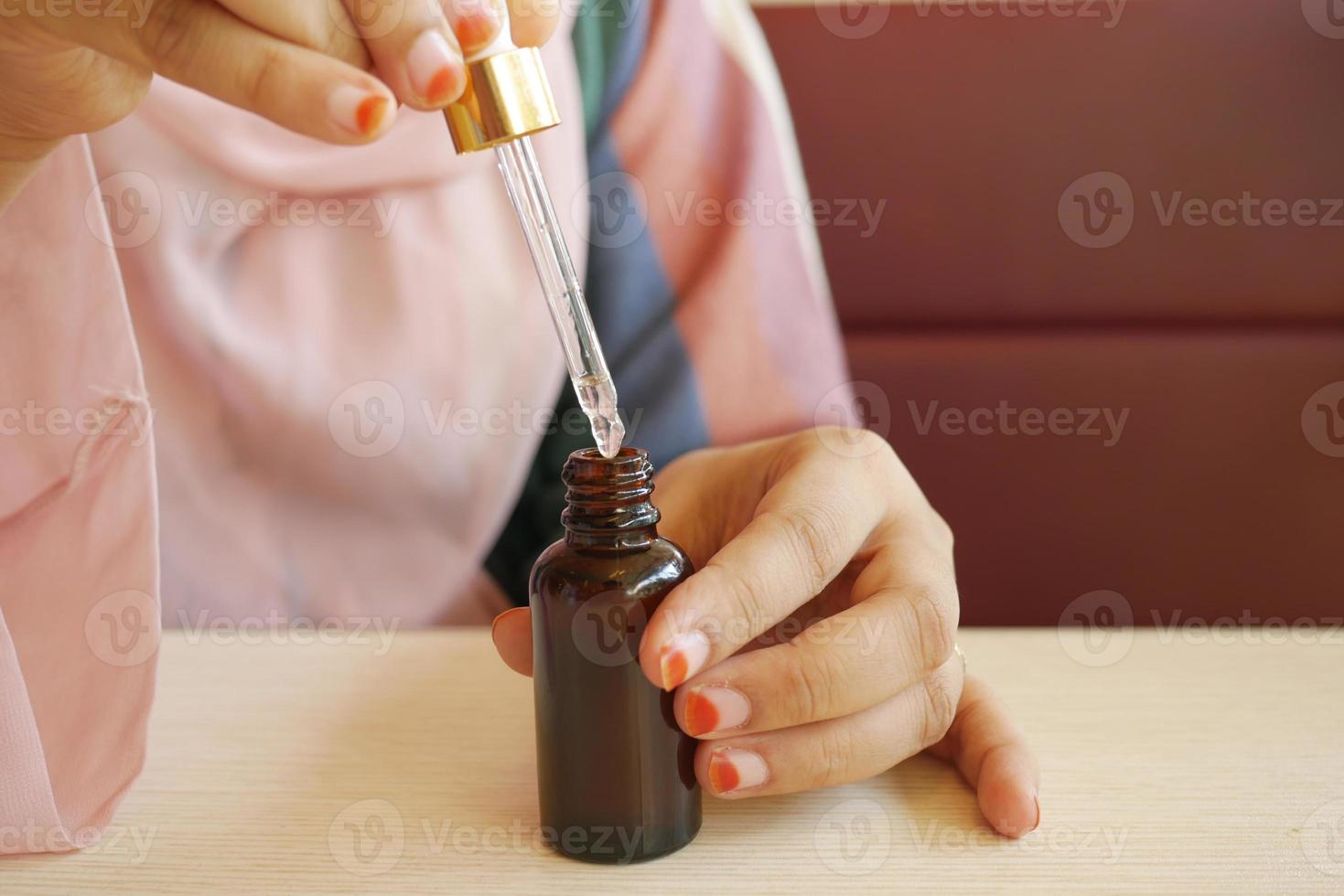 women hand Drop falls from a pipette into a cosmetic bottle photo