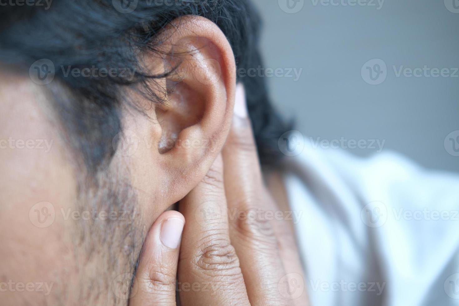 young man having ear pain touching his painful ear , photo