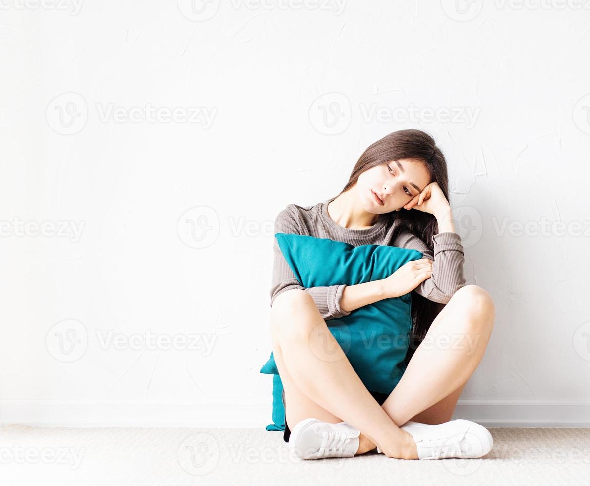 woman in casual clothes sitting on the floor with pillows photo