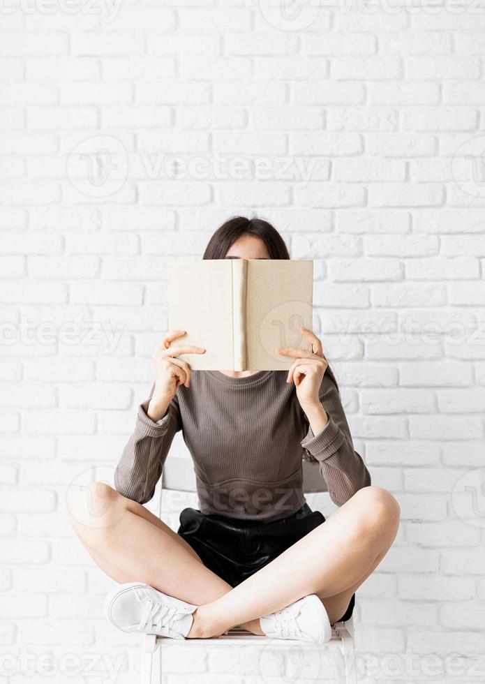 Woman sitting on the chair with legs crossed reading a book photo