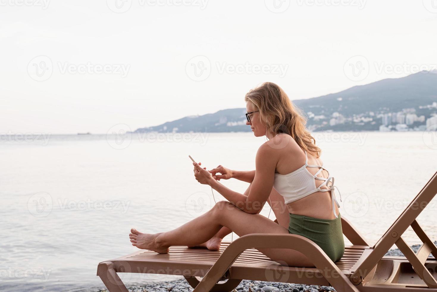mujer sentada en la tumbona escuchando música foto