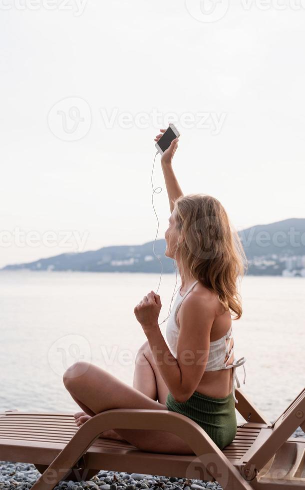 mujer sentada en la tumbona escuchando música y bailando foto