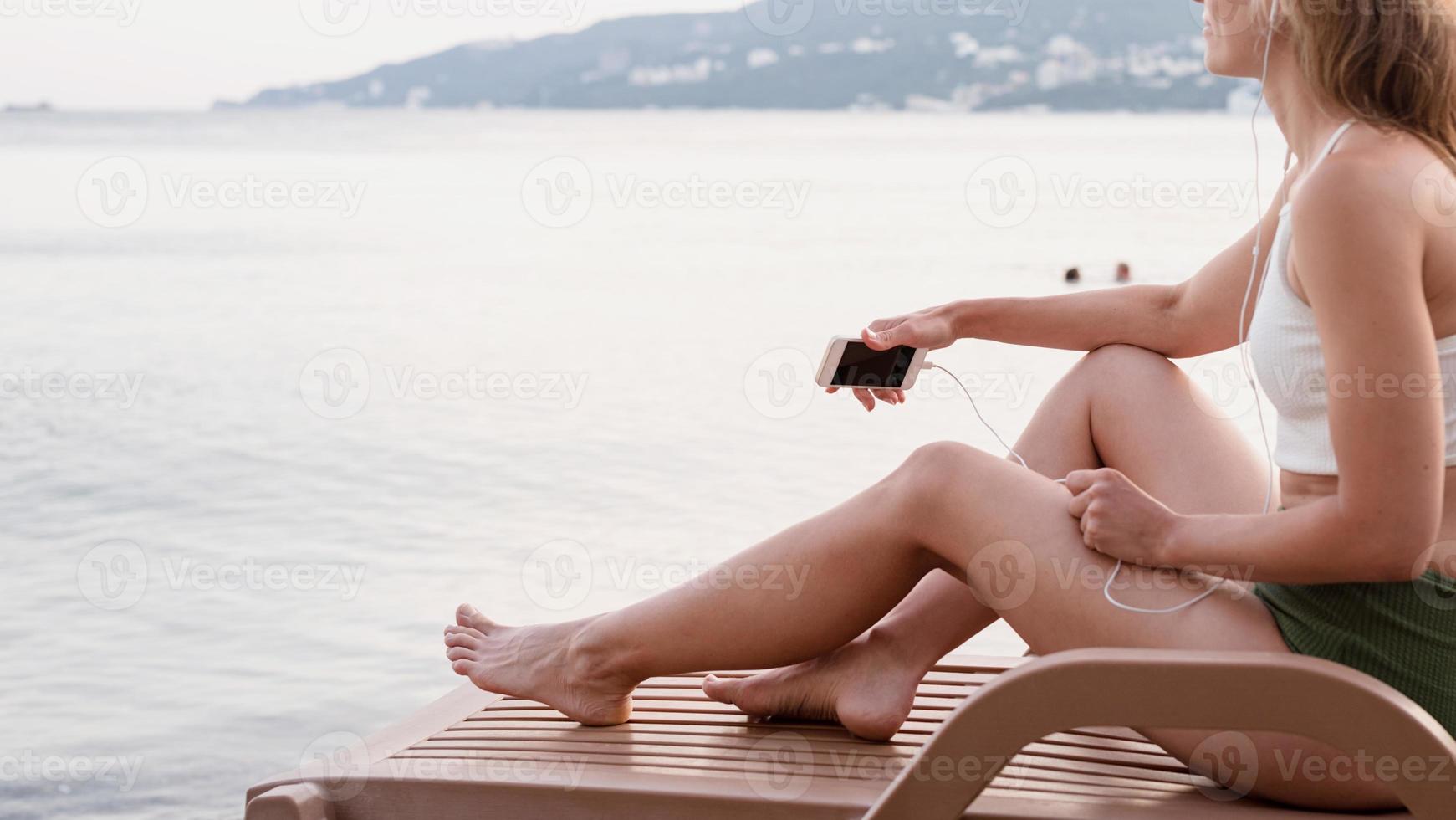 woman sitting on the sun lounger listening to the music photo