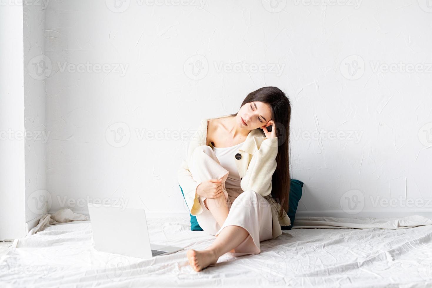 Mujer sentada en el suelo y haciendo un proyecto independiente en la computadora portátil foto