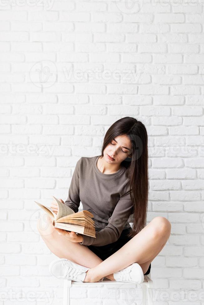 mujer sentada en la silla con las piernas cruzadas leyendo un libro foto