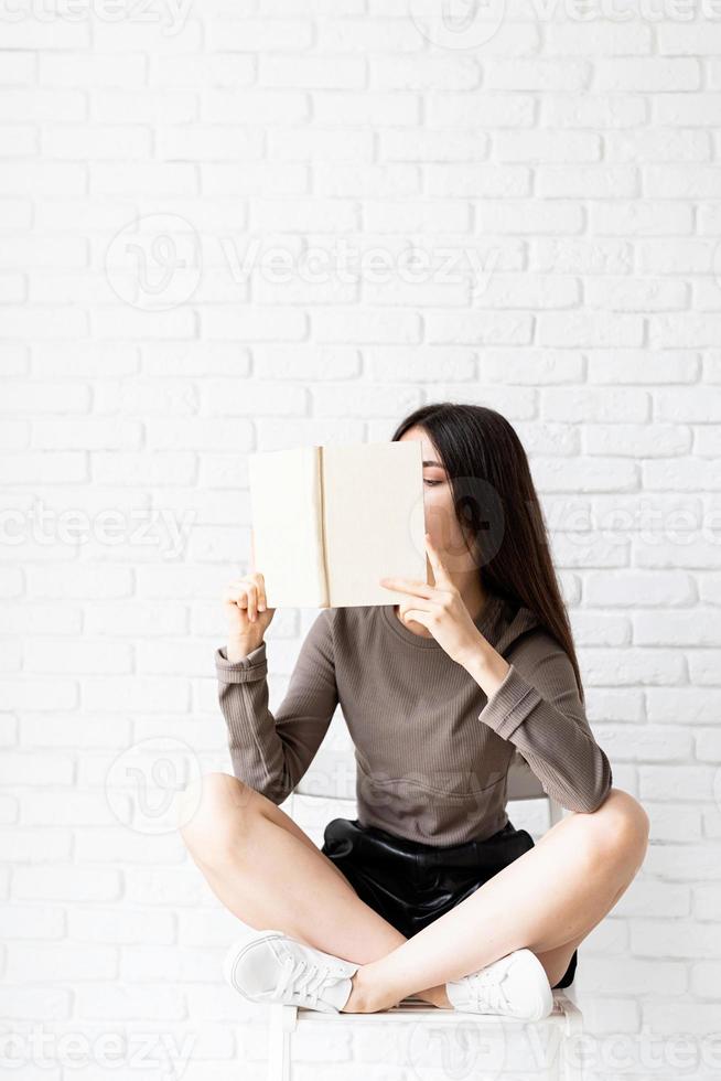 Woman sitting on the chair with legs crossed reading a book photo