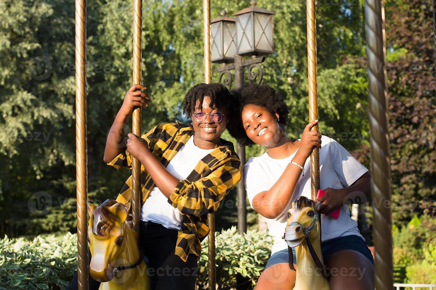 Dos mujeres afroamericanas felices en un parque en un paseo de diversiones foto